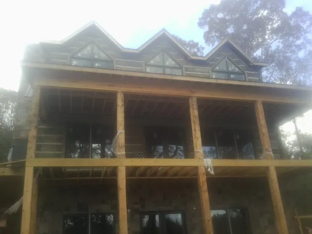 Dormers and porch framing on a large log home under construction — Roof Coating work by our crew in Attica